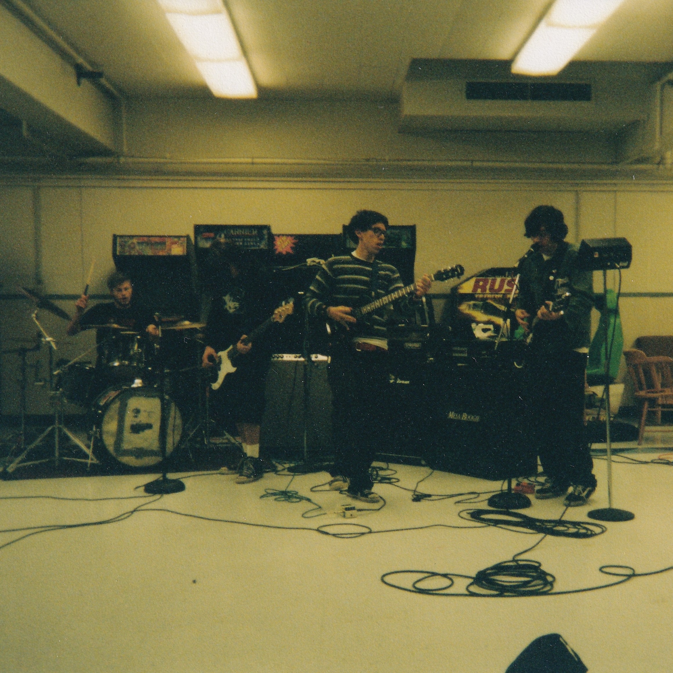 Band playing music in a garage with equipment and instruments.